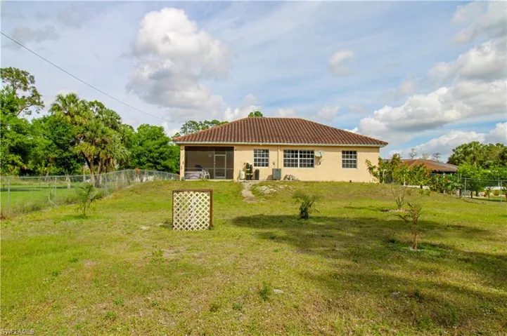 Back of house with a tile roof, a yard, stucco siding, a sunroom, and a fenced backyard