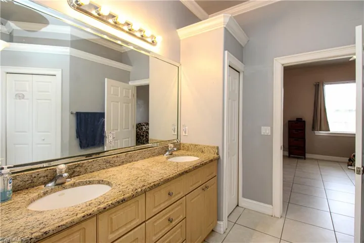 Full bathroom featuring crown molding, a closet, a sink, and tile patterned floors