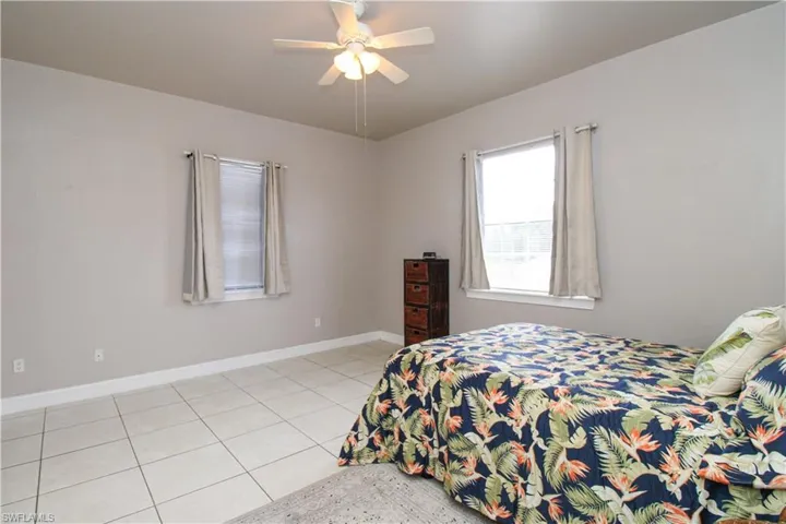 Bedroom featuring ceiling fan, light tile patterned flooring, and baseboards