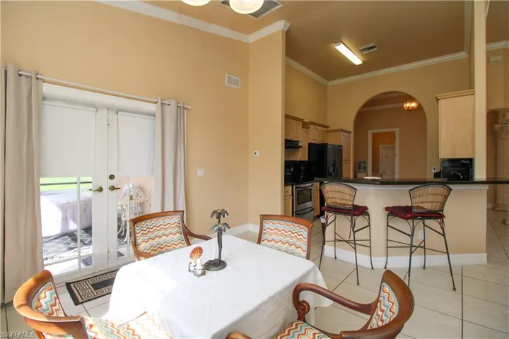 Dining space featuring light tile patterned floors, visible vents, arched walkways, and ornamental molding
