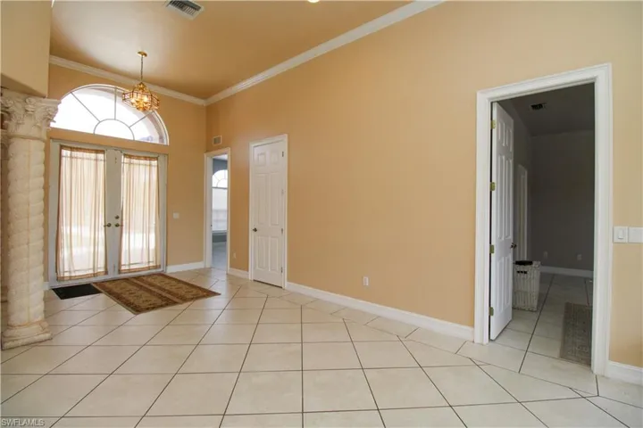 Entryway featuring light tile patterned floors, visible vents, baseboards, french doors, and crown molding