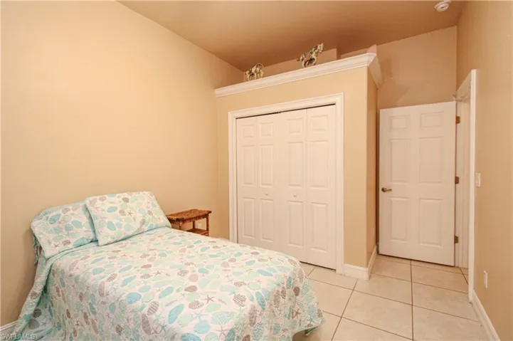 Bedroom with light tile patterned floors, a closet, lofted ceiling, and baseboards