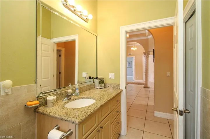 Bathroom featuring crown molding, tile walls, decorative columns, vanity, and tile patterned flooring
