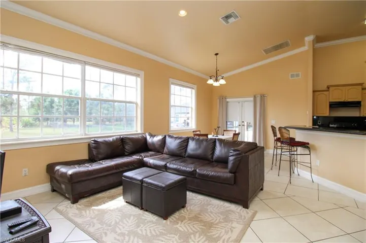 Living area with visible vents, crown molding, and light tile patterned flooring