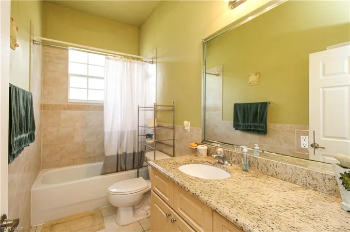 Full bathroom featuring shower / tub combo, vanity, toilet, and tile patterned floors