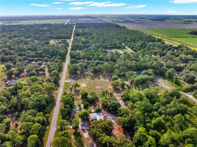 Expansive aerial landscape featuring a paved road traversing a verdant, wooded area