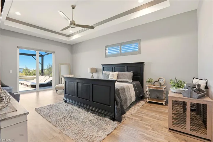 Primary Bedroom featuring access to outside, ceiling fan, light wood-style floors, recessed lighting, and a raised ceiling