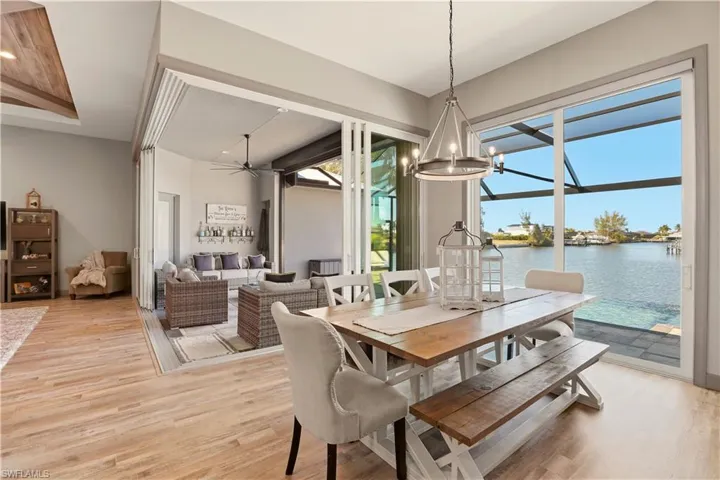Dining space featuring light wood-style floors, ceiling fan, a water view, and a chandelier