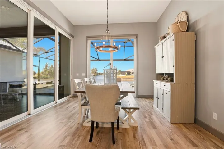 Dining space featuring a chandelier and light wood finished floors with Sliding Door to the Pool area and to the covered lanai area.