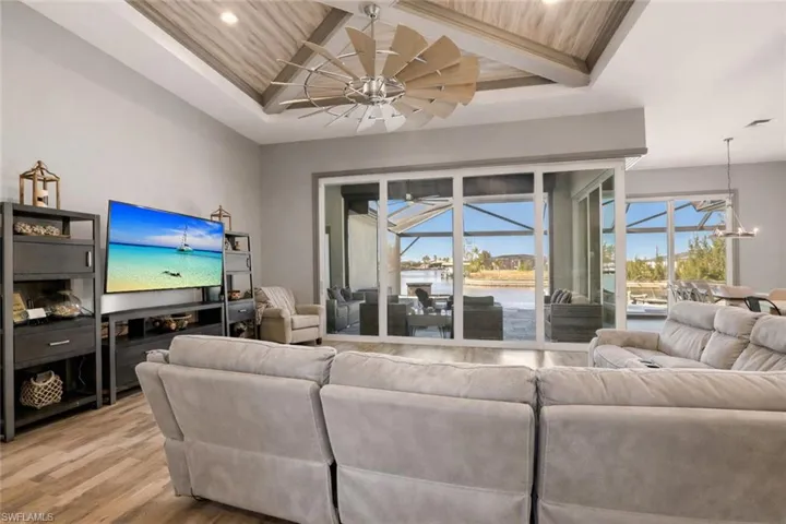 Living area with healthy amount of natural light, a covered lanai, light wood finished floors, recessed lighting, and a wooden ceiling with custom millwork exposed beams.