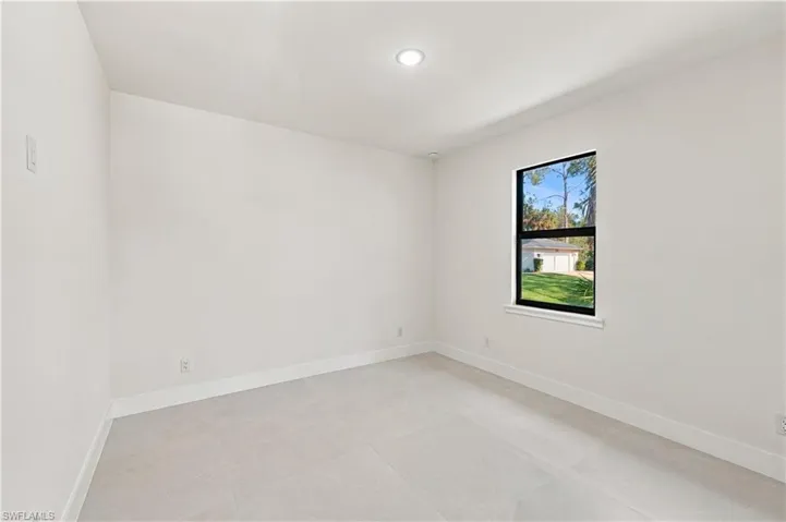 Recessed ceiling lighting, a large window with black trim, and light-toned flooring