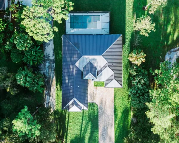 Modern metal roof, geometric architectural design, screened swimming pool, extensive gravel driveway, and surrounding mature landscaping