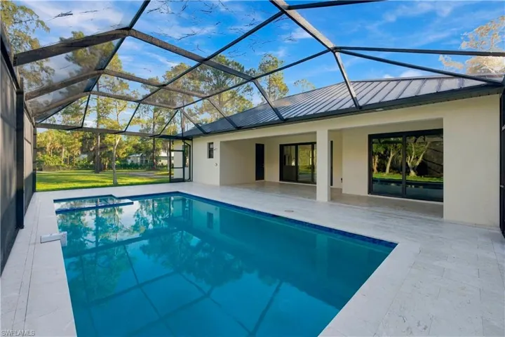 Screened pool enclosure featuring a rectangular pool with an integrated spa
