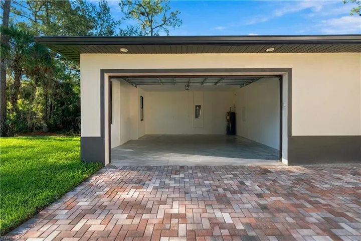 Multi-tone paver driveway, an attached garage with an open bay, and a concrete floor
