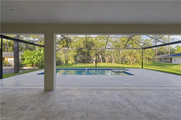 Screened patio with a rectangular swimming pool, integrated spa, and expansive paver decking