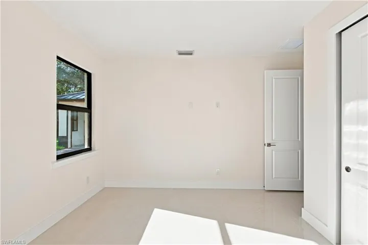 White paneled door with brushed nickel hardware, black-framed window, and light-toned flooring