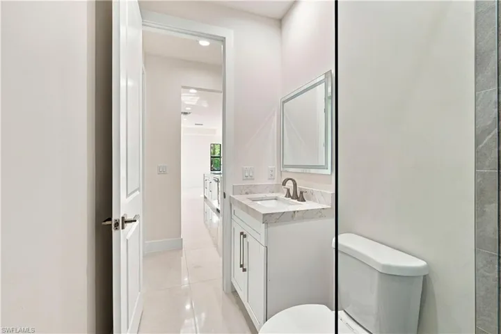 Contemporary vanity with a stone countertop, under-mount sink, and framed mirror