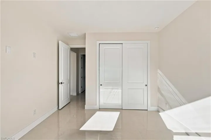 Neutral wall finishes, recessed lighting, white trim, sliding panel doors, and tile flooring