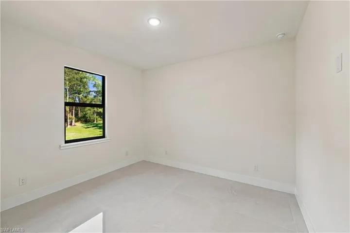 Recessed ceiling lighting, a single window with black framing, and neutral-toned wall paint