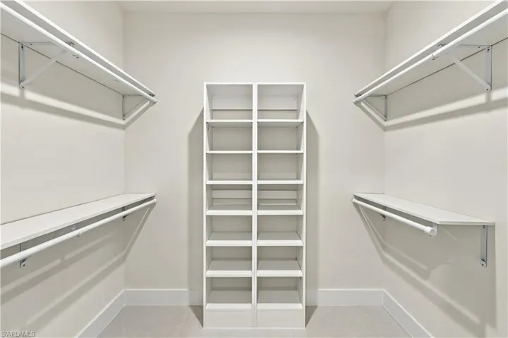 Walk-in closet featuring built-in shelving, multiple hanging rods, and light-colored walls