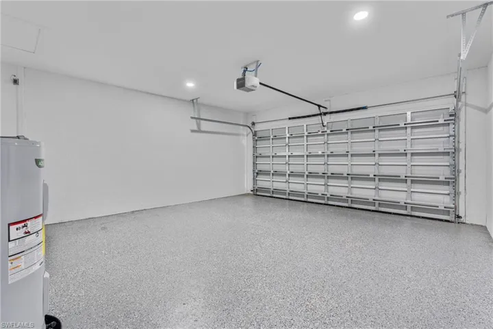 Garage with water heater, recessed lighting, and a garage door opener