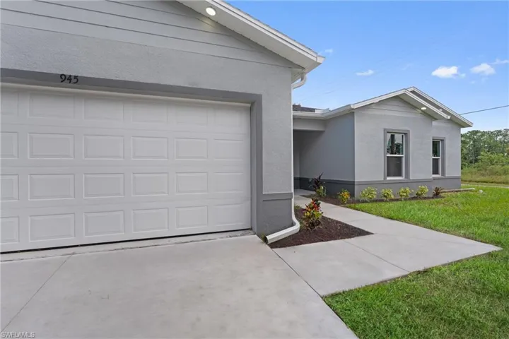 View of front facade featuring stucco siding, a garage, driveway, and a front yard