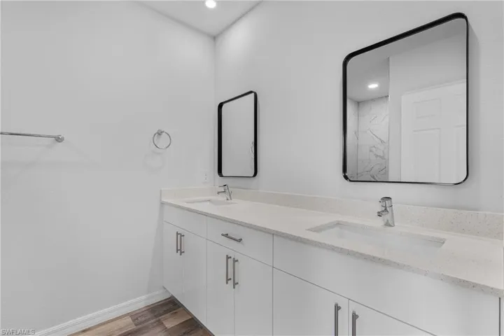 Bathroom featuring dark wood-style floors, double vanity, and recessed lighting
