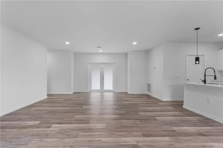 Unfurnished living room featuring recessed lighting, light wood-style flooring, and french doors