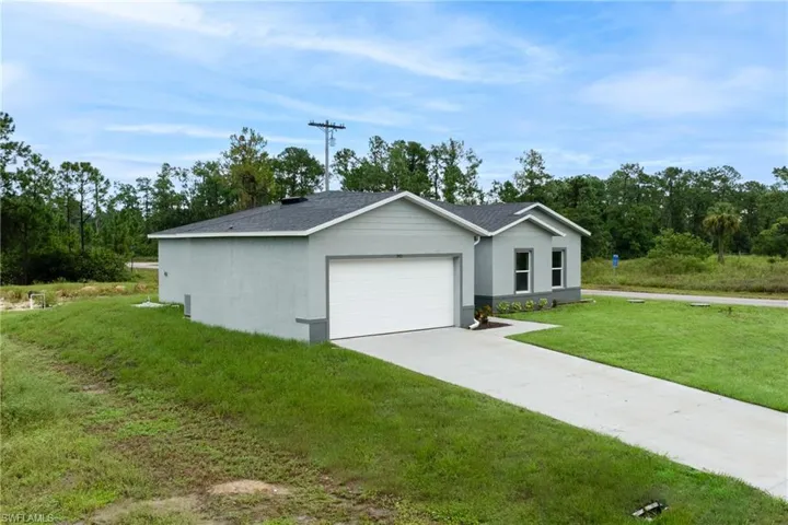 Ranch-style house featuring driveway, stucco siding, a garage, and a front yard