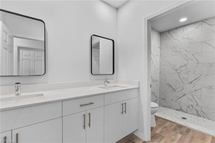 Bathroom featuring a shower stall, light wood-style floors, and double vanity
