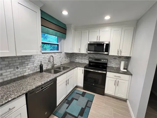Kitchen with electric stove, sink, black dishwasher, and backsplash