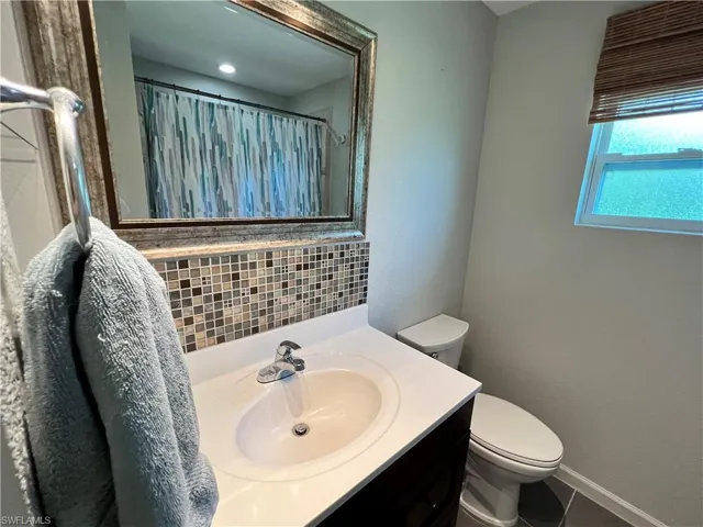 Bathroom with tile flooring, tasteful backsplash, toilet, and large vanity