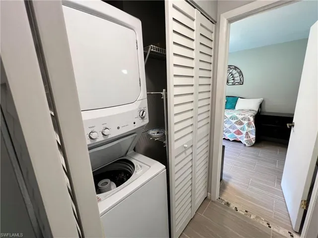 Clothes washing area with stacked washer / dryer and tile flooring