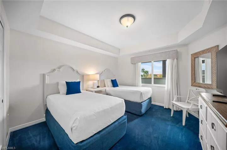 Bedroom with a tray ceiling and dark carpet