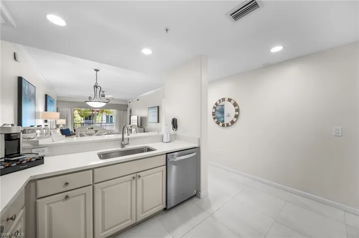 Kitchen with dishwasher, pendant lighting, open floor plan, light stone countertops, and light tile patterned flooring