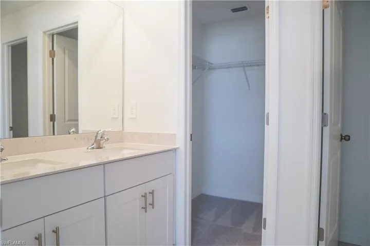 Full bathroom with double vanity, a walk in closet, and carpet floors
