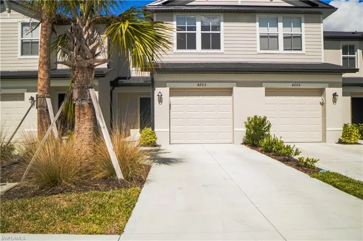 Traditional-style house featuring a garage, concrete driveway, and stucco siding