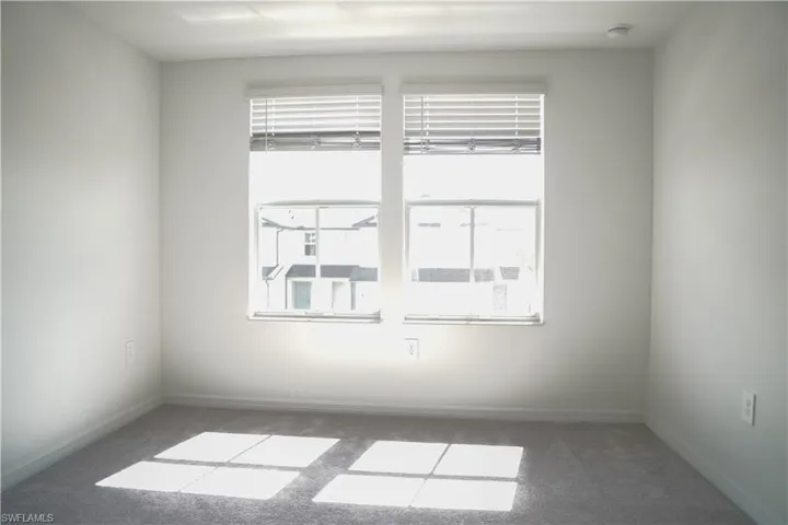 Spare room with dark carpet and baseboards