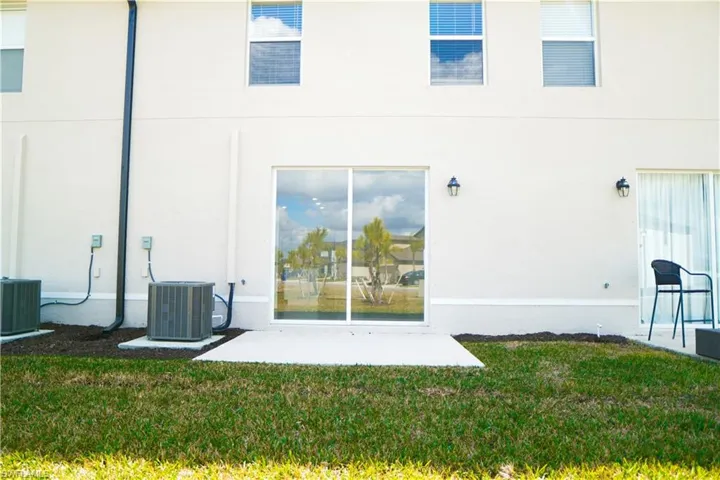 Back of house with a lawn and stucco siding