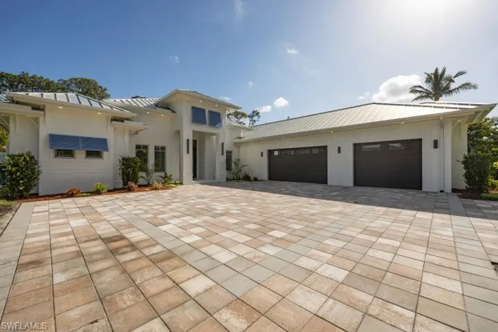 View of front of house with decorative driveway, a standing seam roof, metal roof, and a garage