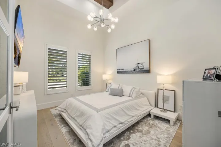 Bedroom with a chandelier, light wood-type flooring, and baseboards