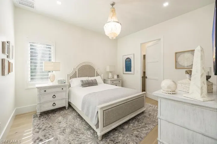 Bedroom with light wood finished floors, baseboards, a chandelier, and recessed lighting