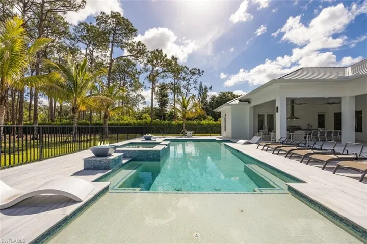View of pool with an in-ground hot tub & fire bowls