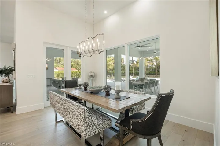 Dining area featuring baseboards, light wood-type flooring, recessed lighting, a towering ceiling, and a ceiling fan