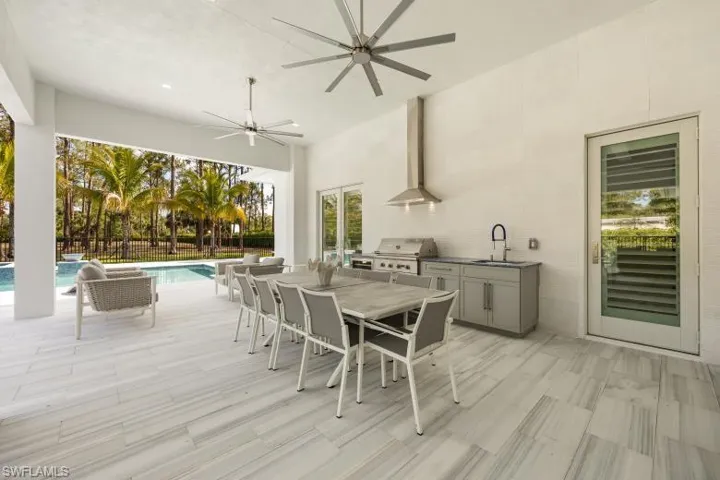 View of patio featuring a sink, an outdoor kitchen, a grill, outdoor dining space, and a ceiling fan