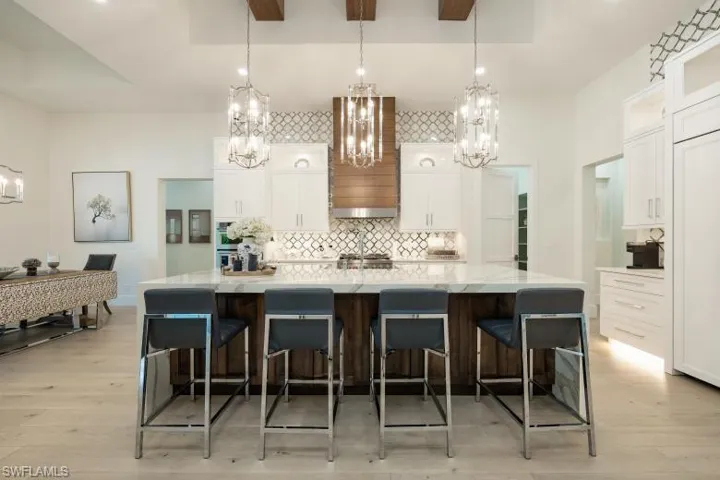 Kitchen with a chandelier, tasteful backsplash, white cabinets, and light wood finished floors