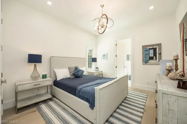 Bedroom with light wood finished floors, a chandelier, baseboards, and recessed lighting