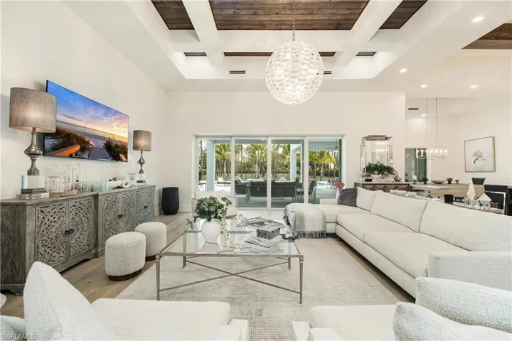 Living room with a chandelier, wood finished floors, coffered ceiling, a high ceiling, and beamed ceiling
