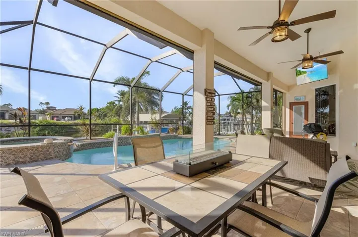 View of patio with ceiling fan, a swimming pool with hot tub, and glass enclosure
