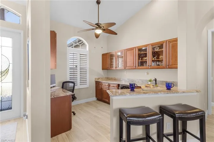 Kitchen with light wood-type flooring, plenty of natural light, kitchen peninsula, and light stone countertops